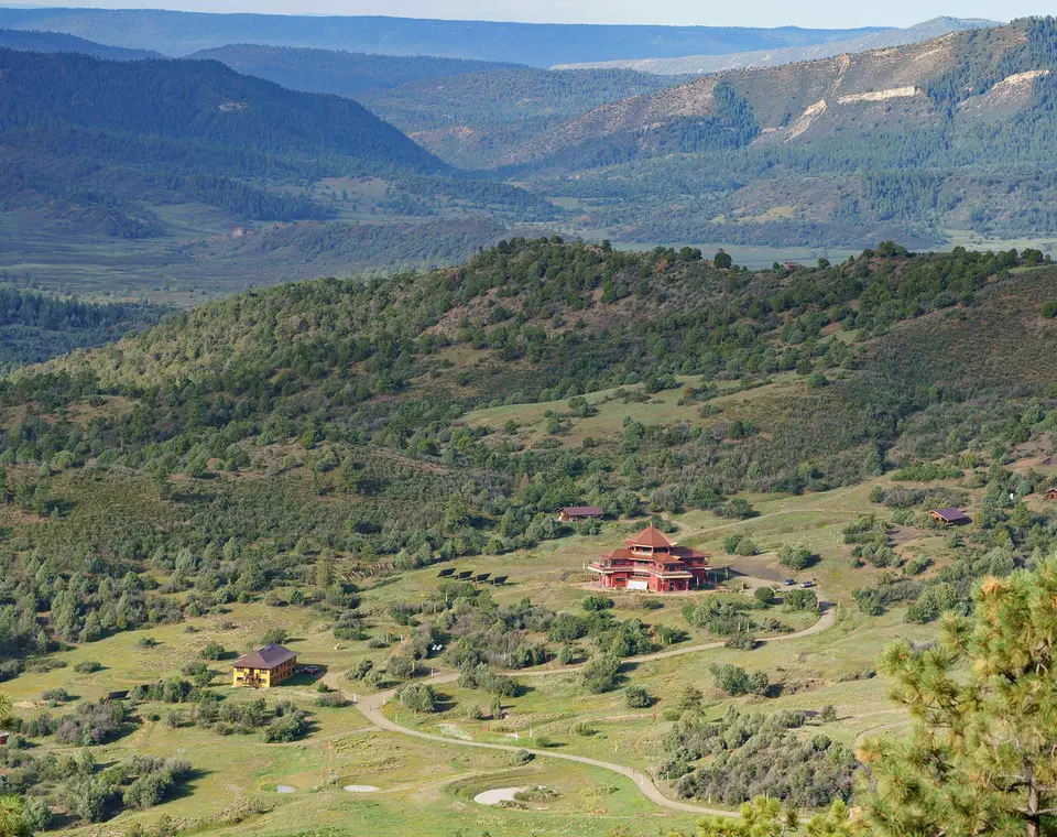The Tara Mandala land from above, with the temple set among forested ridges and open valleys