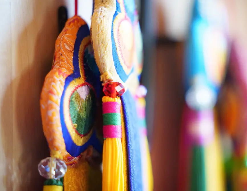 Embroidered dharma textiles and bright tassels hanging in soft light